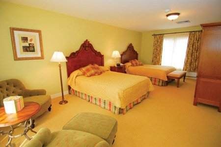 A hotel room with two beds and a chair, perfect for families with kids.