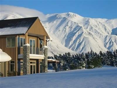 A house with snow covered mountains in the background, showcasing winter fun on New Zealand's South Island.