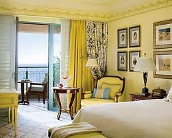 A glamorous yellow bedroom with a balcony overlooking the ocean at the Four Seasons Alexandria in Egypt.