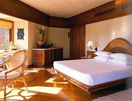 Enjoy total 'aman' at Amanpulo, a room with a bed and a wicker chair.