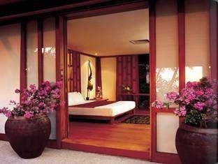 A serene retreat: Amanpuri's bedroom with a bed and bedside table.