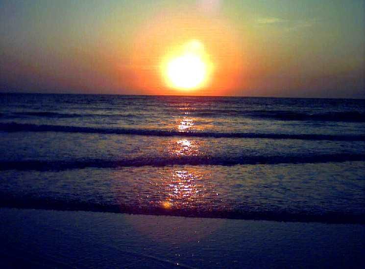 The sun is setting over the ocean with waves in the background, showcasing the popular Goanese beaches.