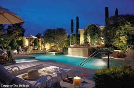 A rare experience awaits you at Bellagio Villas with a pool and lounge chairs at night.