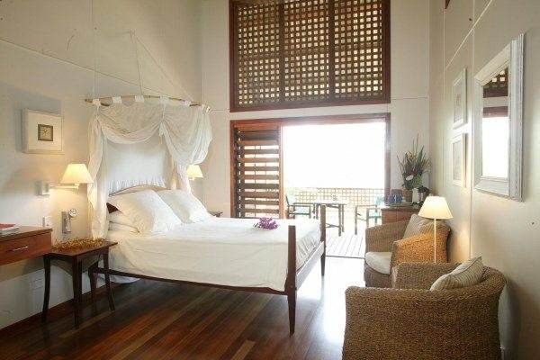 A beach house with beds surrounded by the Great Barrier Reef and Daintree Rainforest at Bloomfield Lodge.