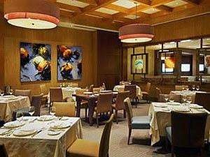 A restaurant with wooden ceilings and tables and chairs.