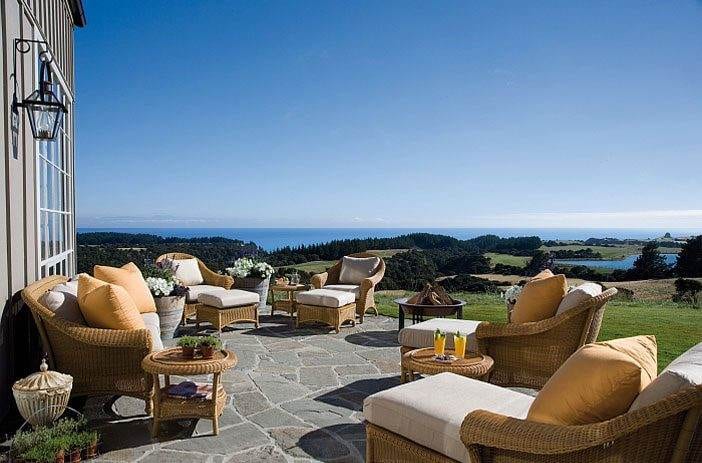 A patio with wicker furniture and a scenic ocean view.