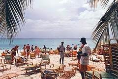 A group of people on a beach under palm trees enjoying their holiday in style at Grand Cayman Resort.