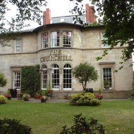         A large house with a lot of greenery around it in England.
