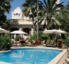 A hotel with a pool and lounge chairs surrounded by palm trees, perfect for a sunny getaway in Mallorca pt.2.