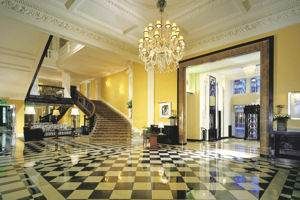 A large lobby with a checkered floor and a chandelier at Claridge's.