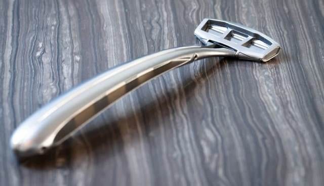 A stainless steel Zaffiro razor on a wooden surface.