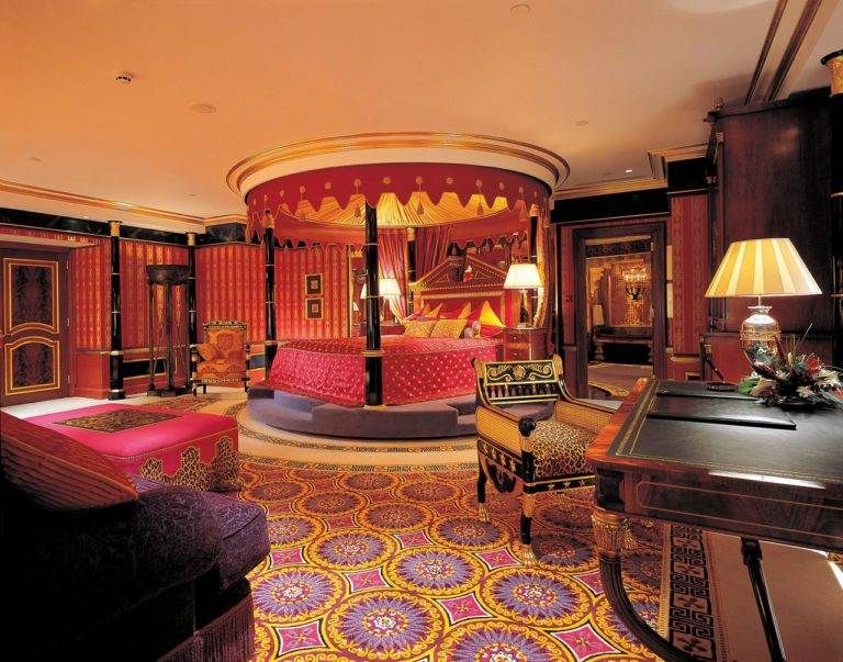 An ornate bedroom with a bed and a desk located in the Arabian-themed suite at Burj Al Arab, where guests can sail away into luxury.