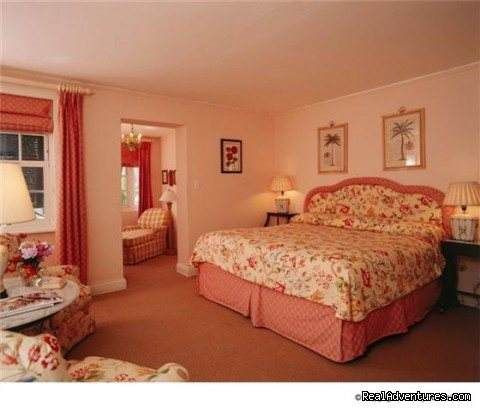 A pink bedroom with a bed and a chair showcasing history from 300 years ago.