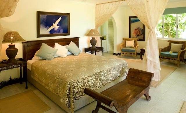 A bedroom with a canopy bed and chairs, perfect for a honeymoon amidst rare birds and turtles at the Cousine Island Resort and Spa.
