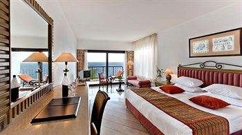 A hotel room with a large bed and a view of the ocean at Divan Antalya.