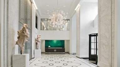 The Elysian Hotel - Chicago: A luxurious hallway with marble floors and a chandelier.