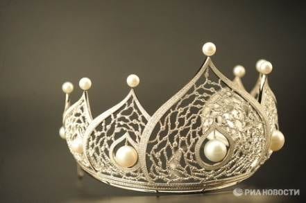 A silver crown with pearls on it.