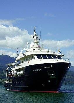 A large boat in the water with mountains in the background, offering a luxurious fishing trip experience.