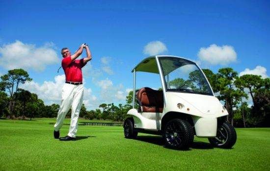 A man is driving a luxurious golf cart on a golf course to surprise golfers.