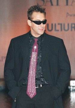 A man in a suit and tie standing on a runway wearing an expensive designer necktie.