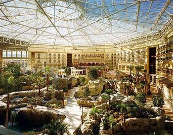 The atrium of a hotel with a waterfall and palm trees, offering a unique experience at Gaylord Palms in Kissimmee, Fla.
