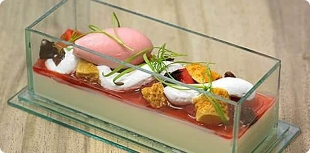 A dessert in a glass dish with strawberries and cream, served at a UK Pub Grub.