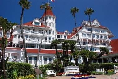 A large white building with palm trees in front of it, offering a truly memorable stay at the legendary Hotel del Coronado.