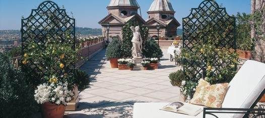 A balcony with chairs and flowers on it at a legendary hotel in Rome.
