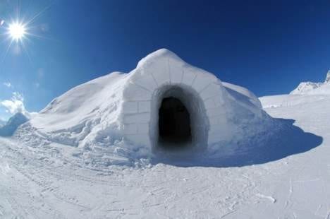 A luxurious igloo with a door in the middle of the snow.