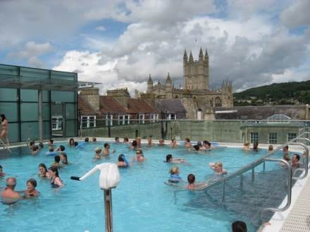 A large group of people enjoying themselves in an outdoor swimming pool in Bath, England.