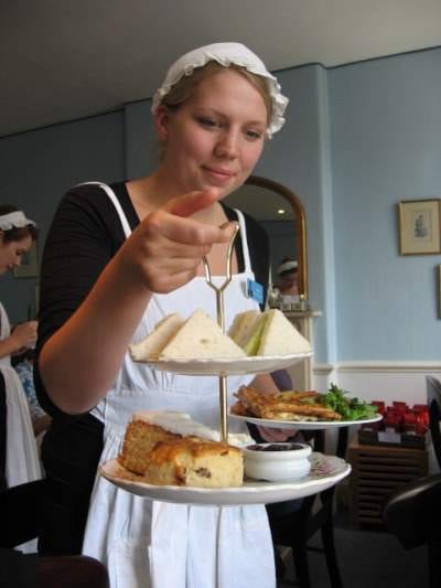 A woman in a white apron serving food in Bath, England.