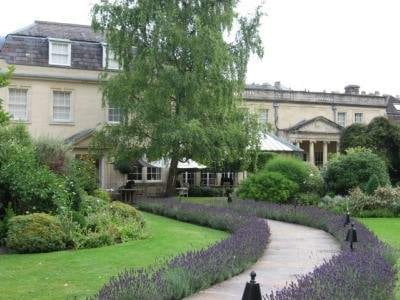 A pathway leading to a house in England with lavender plants.