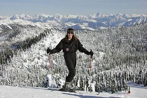 A woman on skis standing on a snow covered slope in Montana's Glacier Country.