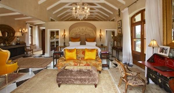 Rediscover the hospitality of Franschhoek wine country at La Residence, featuring a bedroom with an ornate ceiling and chandelier.