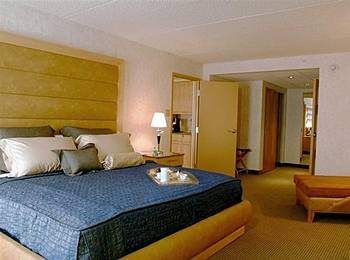 A hotel room with a bed and a television, embodying French spirit and Caribbean soul at La Samanna.