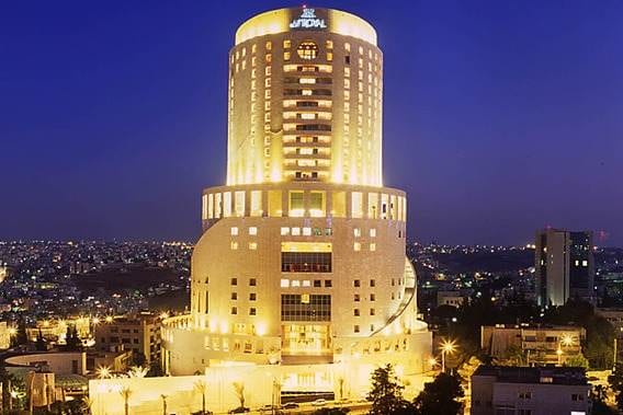Le Royal Hotel, a large building lit up at night with a city in the background, embodies the heartbeat of Amman.