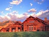 A large log home in the middle of a grassy field at Sun Ranch.