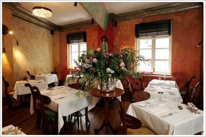 A restaurant with tables and chairs and flowers on the table that provides a memorable dining experience at M at the Fringe.