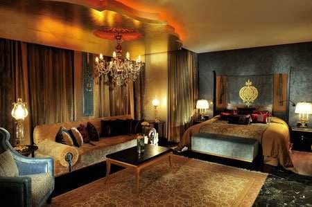 A luxurious bedroom with a large bed and a chandelier located in the Mardan Palace Hotel, Turkey.