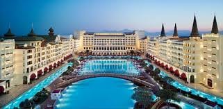 An aerial view of a hotel pool at dusk offers a surprising vacation experience at The Turkish Mardan Palace.