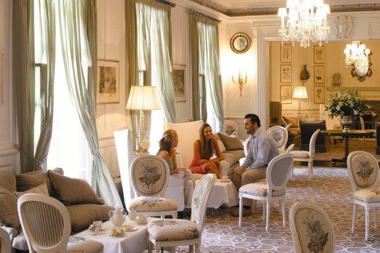 A group of people sitting in The Mount Nelson Hotel, an ornate 19th century classic style romantic hideaway.