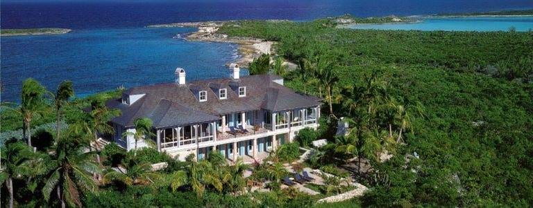 An aerial view of a romantic house on top of a hill overlooking the ocean.