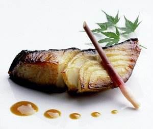 A piece of black cod is sitting on a white plate.