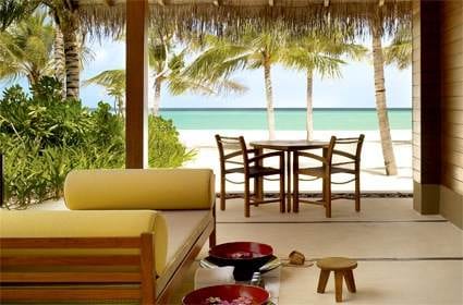 A living room with a table and chairs overlooking the ocean at One&Only Resorts in Maldives.