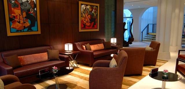 A lobby with brown leather furniture and paintings redefines the oasis environment at Desert Palm Dubai.