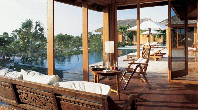 Teak wood furniture paired with a poolside view in an idyllic setting at Parrot Cay.