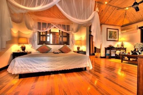 A luxurious bedroom with a canopy bed and wooden floors.
