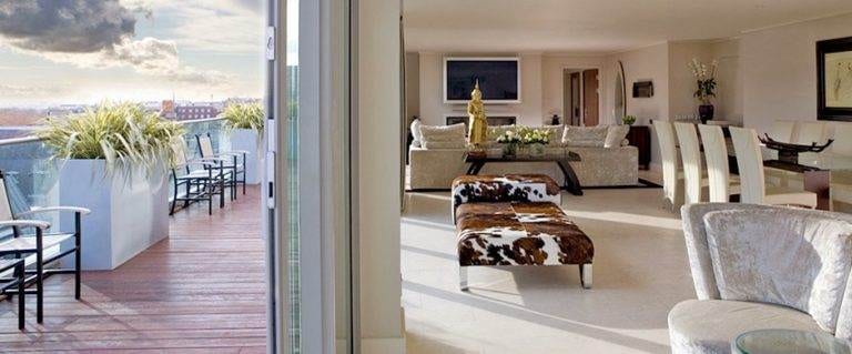 The Penthouse Suite – a living room with a balcony overlooking the city.