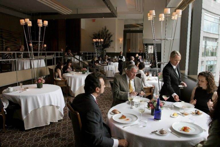 A group of people sitting at a table in a restaurant, Taste the Exclusive Five-Course Meal at Per Se - NYC.
