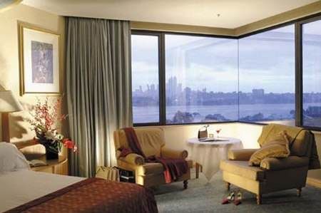 A hotel room with a large bed and a view of the city in Hotel Perth Burswood.